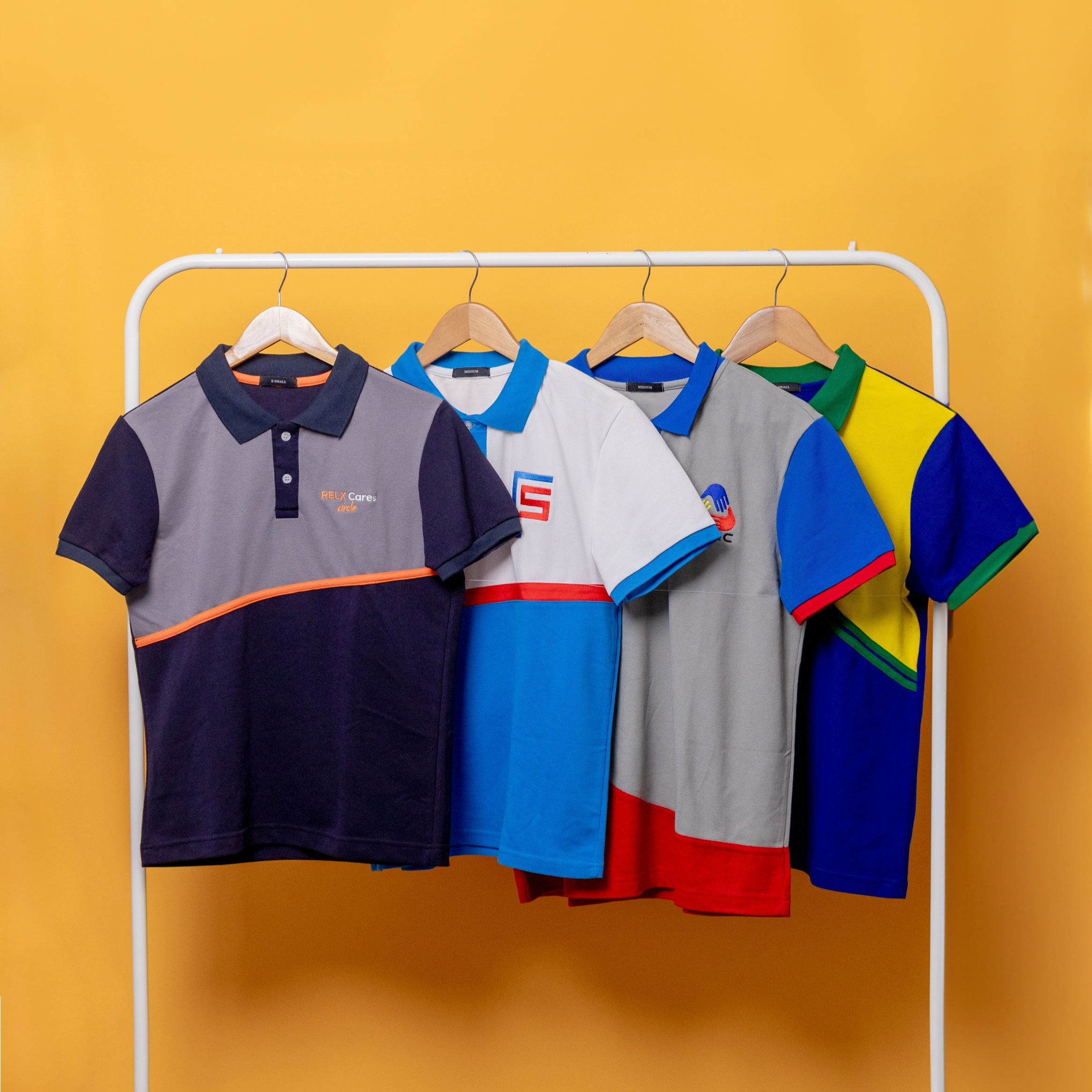 Colorful polo shirts on a white rack against a yellow background